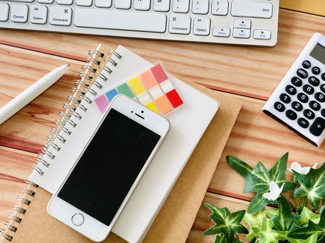 テーブルにメモ帳やスマホが置いてある様子